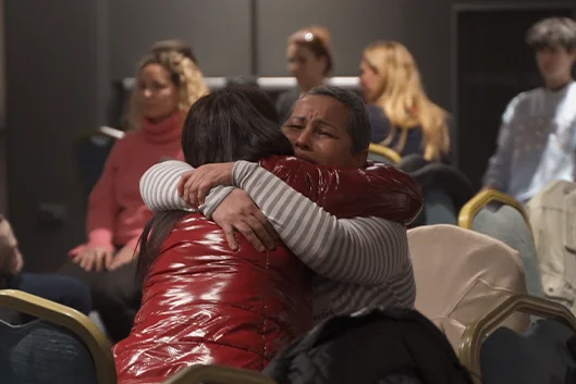 Abrazo emotivo entre participantes durante un proceso
